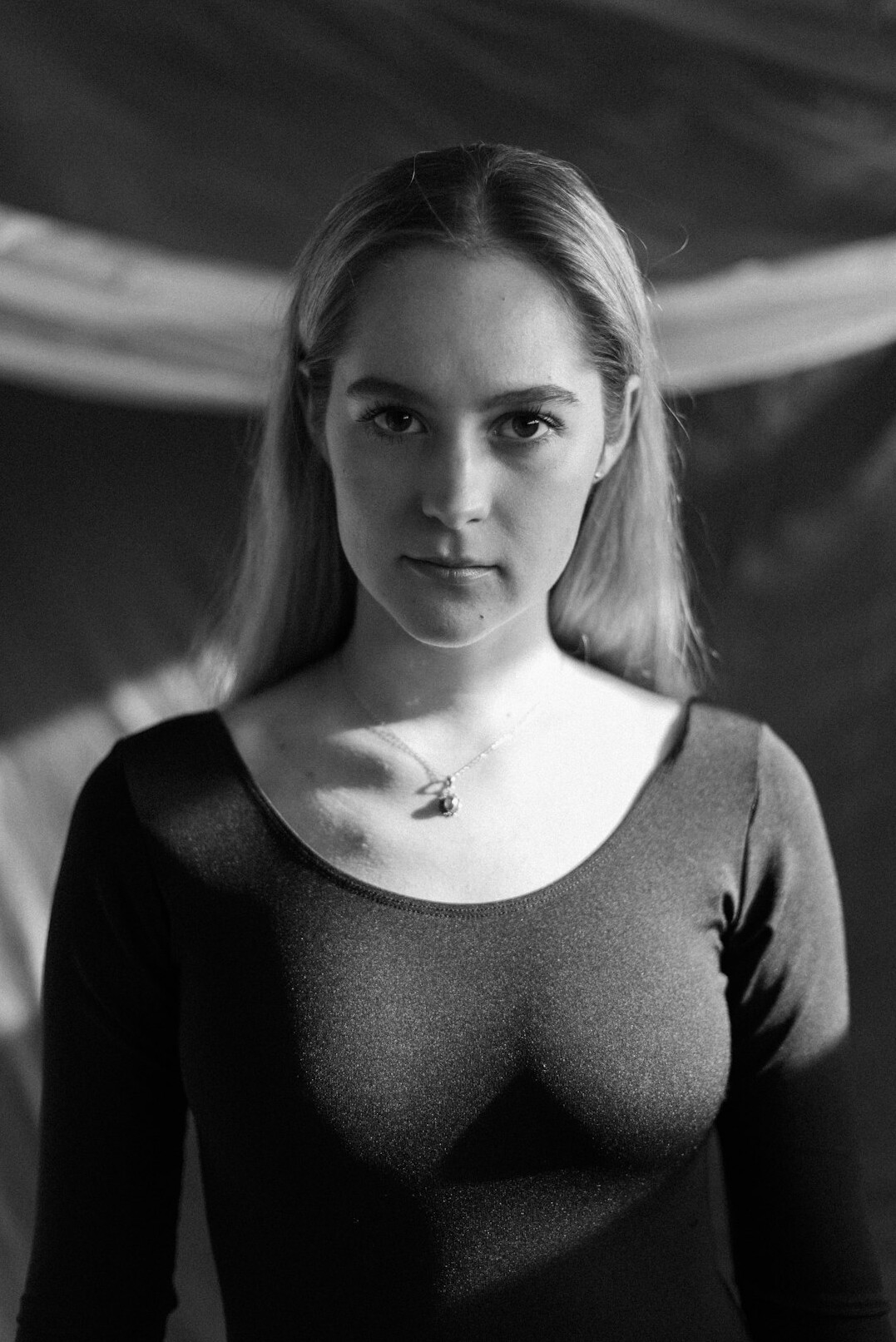 Studio portrait of a white woman in her thirties with a camera around her neck