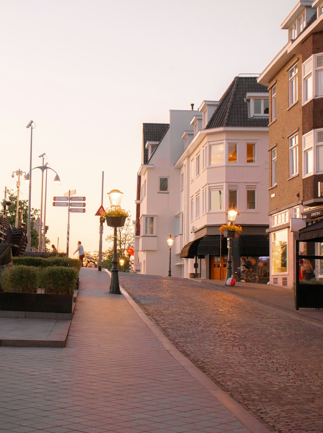 Quiet city street corner with a lamp post and storefronts in early morning light